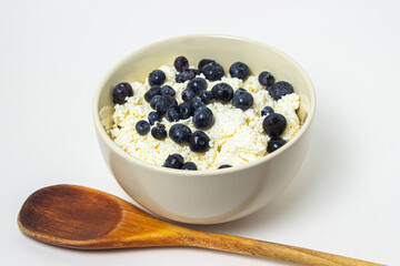 Cottage cheese with blueberries on a white background. Useful and tasty breakfast.