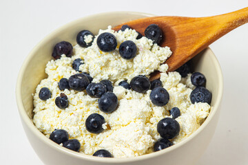 Cottage cheese with blueberries on a white background. Useful and tasty breakfast.