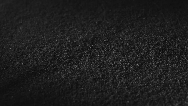 Carbon powder or black charcoal powder. Dark textured background. Volcano dust moving on surface, close-up