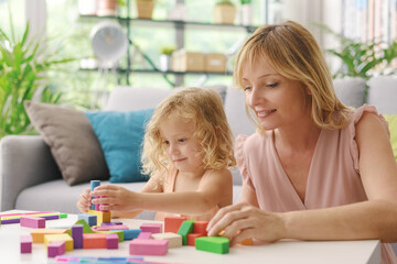 Happy woman playing with her daughter at home