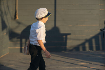 Little ship captain on the deck of a pirate ship. The boy stands on the deck of the ship with a shell in his hands. The boy listens to the sea shell.