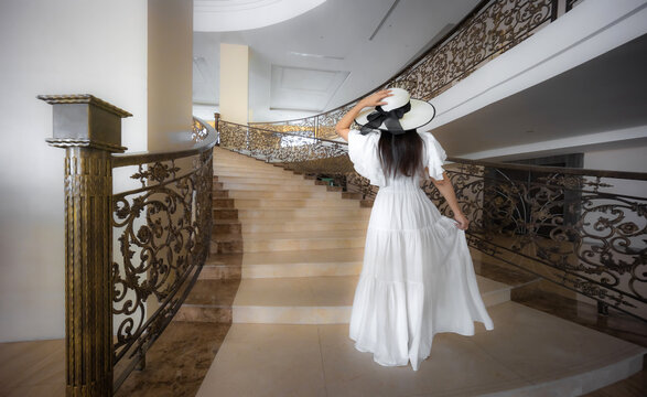 Beautiful young woman in white dress walking up the stairs