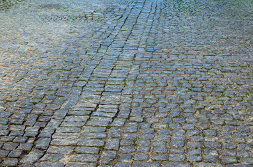 Cobbled road as background. The gray paving stones close up. The texture of the old dark stone. Vintage, grunge. Road surface. Brick stone street road. Pavement abstract texture