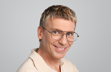 Portrait of smiling mature man standing on light background