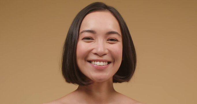 Young Asian brunette shows toothy smile laughing closeup
