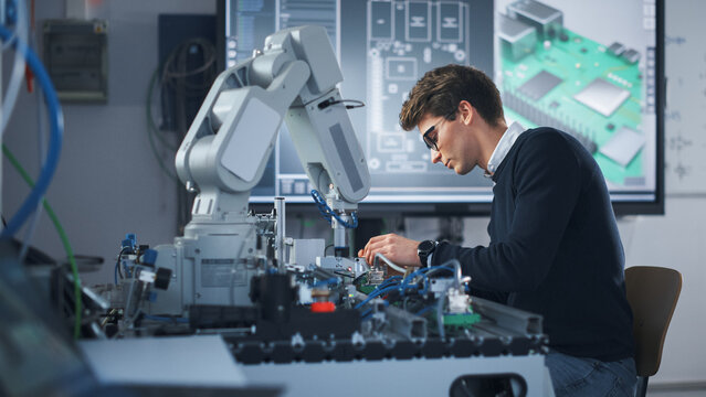 Portrait of Attentive Young Man Engineering Robotic Arm with Screwdriver at Isolated Room. Science Student Holding an Experiment with Bionic Arm. High-Tech Science, Education and Learning Concept