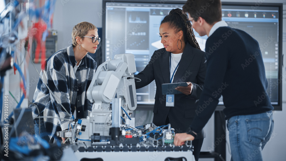 Leinwandbilder University Robotics Class: Black Teacher Explaining Engineering to Students And Using Robot Arm. Diverse Group of Young Engineers Brainstorming while Programming. Computer Science Education Concept.