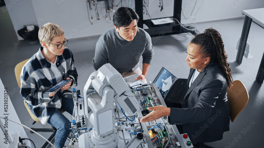 Poster Black Teacher with Laptop and Two Diverse Students Analyse and Discuss Futuristic Robotic Arm During the Lesson. Lecturer Helping with Project. Computer Science Concept. High Angle View.
