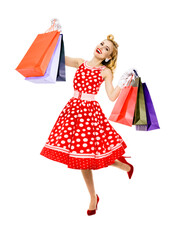 Full body of jumping, running, dancing woman in pinup red dress holding, showing carrying shopping bags, isolated over white background. Sales discounts rebates or consumer bank credit ad concept