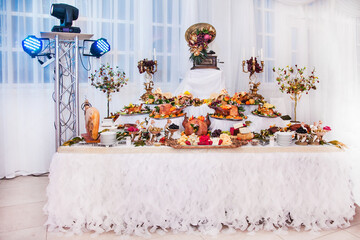 Buffet table with meat snacks, baked pigs in dough, cheese, turkey with fruit, decorated with...