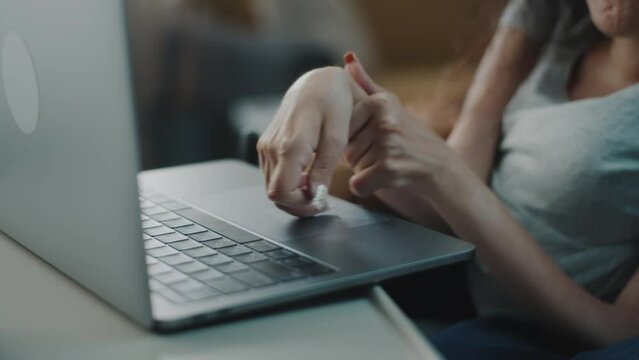 Close shot of the hands of a woman with spinal muscular atrophy surfing the Internet or social media typing on a laptop keyboard