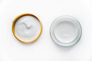A jar of face cream on a white background. Night cream and hand close-up.