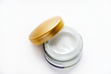 A jar of face cream on a white background. Night cream and hand close-up.