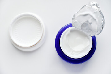 A jar of face cream on a white background. Night cream and hand close-up.