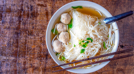.Noodle and meatballs in a bowl on a wooden table