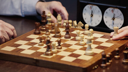 selective focus of chessboard with figures near cropped men playing at home