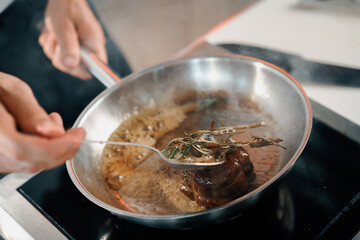 Professional restaurant kitchen, close-up: male chef preparing filet mignon on a frying pan