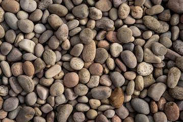 Abstract background of round natural irregular rough rugged brown and beige pebble stones.