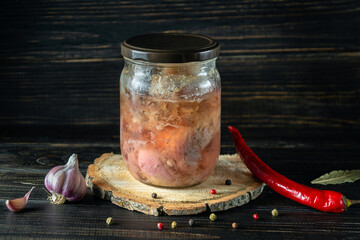 Canned meat or stew in a glass jar with spices on a wooden stand. Farm organic products. Free space...