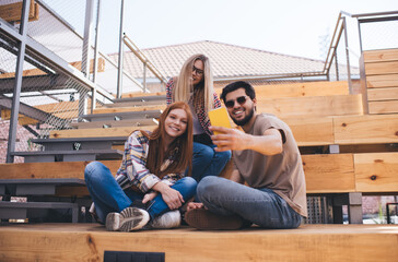 Group of young casual dressed friends posing for selfie on smartphone device. Three millennial people making photo together for social network or blog. Video calling and communication on distance