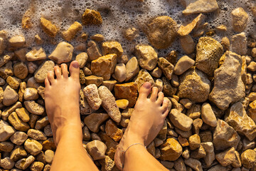 Woman feet on a pebble beach, the Adriatic Sea