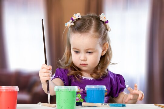 Pretty cute girl draws a drawing in the children's room at the table. A symbol of support and solidarity for families raising children with down syndrome and autist