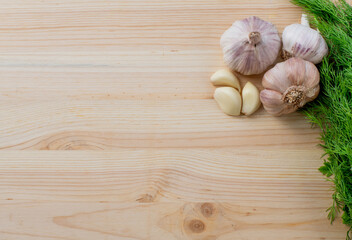 Garlic and herbs on wooden background. Top view, copy space.