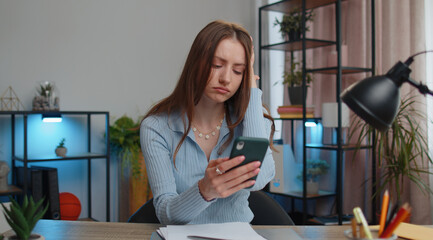 Young business woman use smartphone typing browsing, loses surprised by sudden lottery results, bad...