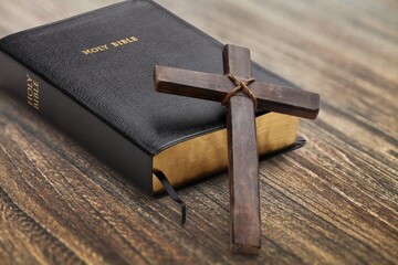 Christian cross leaning on an Holy Bible book in the background. Easter religion faith concept