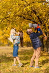 Fototapeta premium A young family with a small child and a dog spend time together for a walk in the autumn park