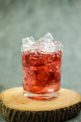 Sparkling red water soda with ice cubes. Summer iced drink