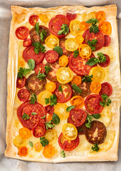 Puff pastry pie with colorful tomatoes and mozzarella, parsley and basil