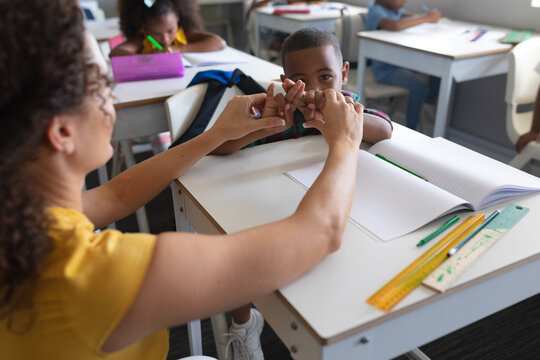 Young Female Caucasian Teacher Teaching Sign Language To African American Elementary Boy In Class