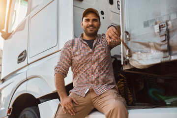 Young happy truck driver by his vehicle looking at camera.