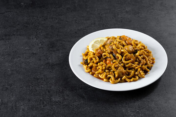Traditional Spanish fideua. Noodle paella on black background. Copy space