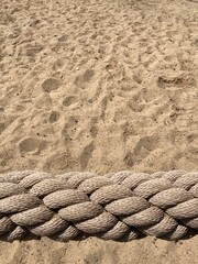Fototapeta na wymiar a braided beige rope in front of a sandy area