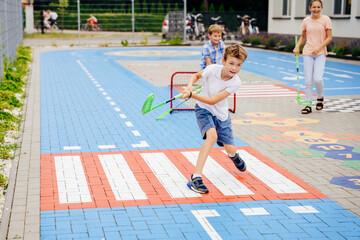 Cheerful children play hockey in the school yard. Activities for kids concept. Summer camp.