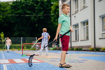 Preteen boy hockey player hitting ball with hockey stick on the playground outdoor. Summer activites for children concept.