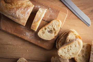 Whole grain bread close-up on the wooden cutting board. Knife with serrated blade. Fresh bread on...