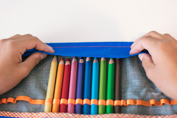 Girl placing her crayons in her blue pencil case. Back to school concept
