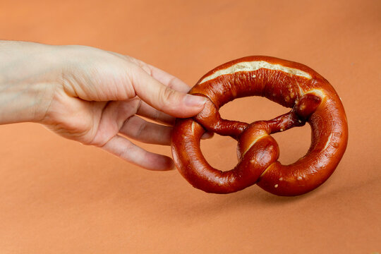 Crop woman showing fresh pretzel
