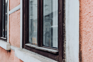 Perspective of a closed window with dark frame on a rustic orange exterior textured wall