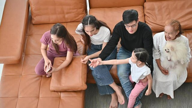 Happy Asian family looking television in room at home
