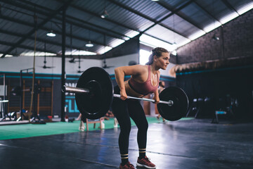 Strong woman in tracksuit have goal training with heavy barbell equipment - pursuit stamina...