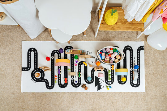 A toy town built in a children's room. Road, cars, trees and wooden blocks for children's  games in playroom. Educational game for baby and toddler in modern nursery.