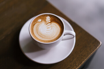 A cup of cafe latter with latte art in white cup with wooden table background