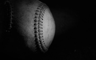 Sports recreation league background with old used baseball close up on black background.