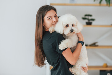 Woman holding the pet. Cute little dog is in the grooming studio