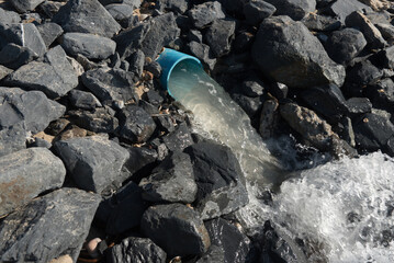 Blue pipe release sea water.Blue pipe is among black stone. 