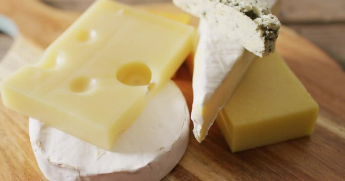 Video close up of assorted hard and soft cheeses on wooden chopping board